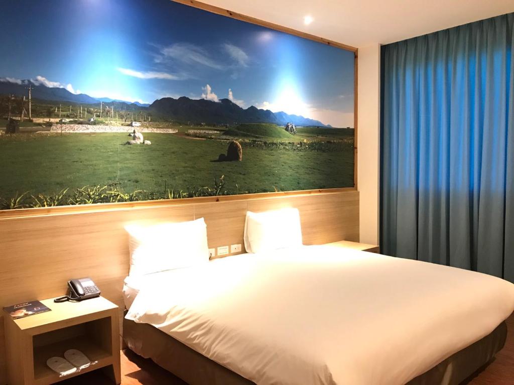 台東市にある綺麗商旅園區館の大きな絵画が壁に描かれたベッド付きのホテルルーム