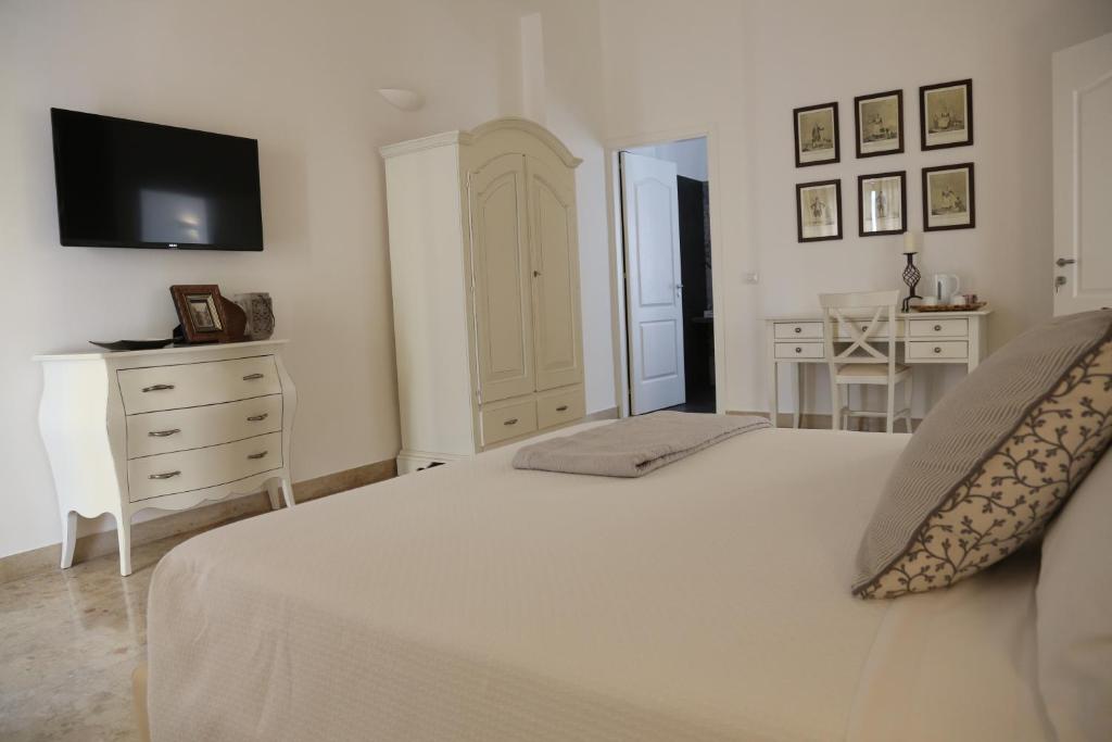 a white bedroom with a bed and a dresser and a tv at Dimi House in Lecce