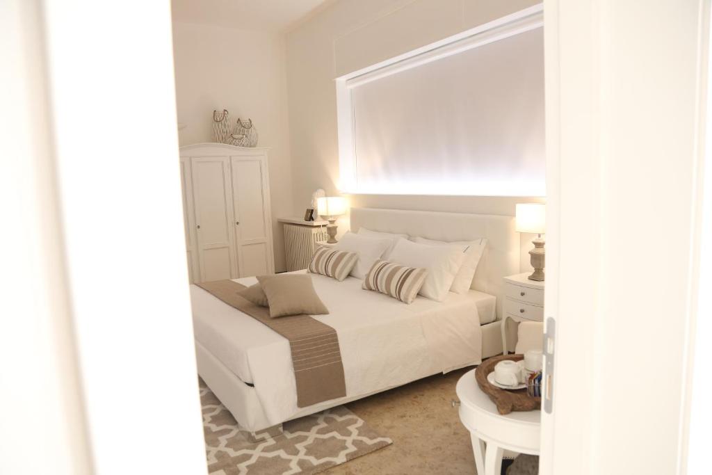 a white bedroom with a bed and a mirror at Dimi House in Lecce