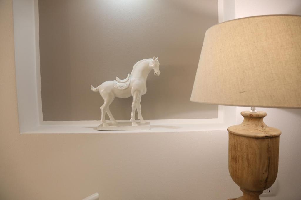a white toy horse on a shelf next to a lamp at Dimi House in Lecce