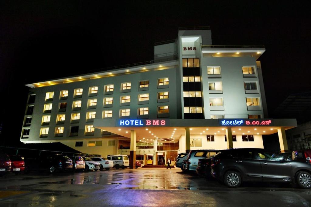 门格洛尔Hotel BMS的一栋酒店大楼，停车场里停满了汽车