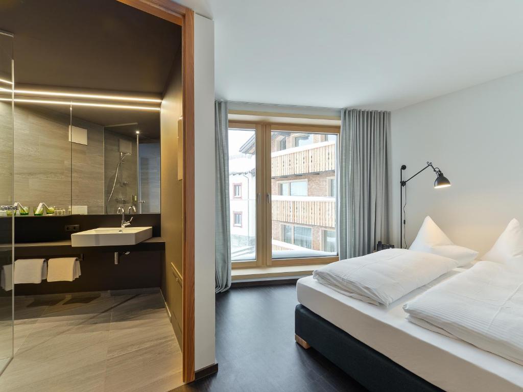 ein Schlafzimmer mit einem Bett und ein Badezimmer mit einem Waschbecken in der Unterkunft Fuxbau in Stuben am Arlberg