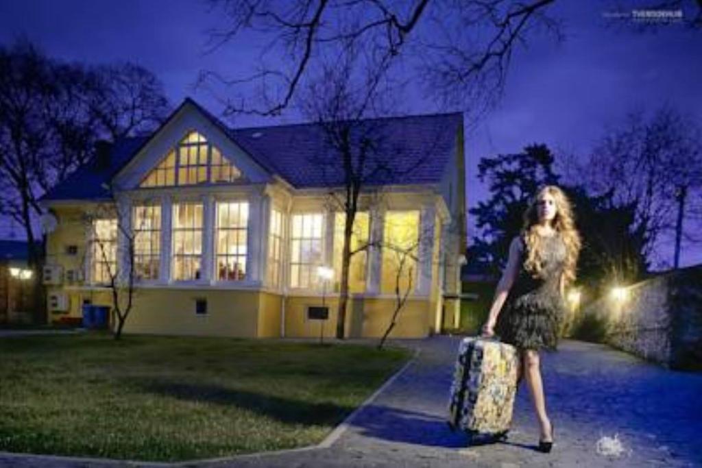 a woman standing in front of a house with a suitcase at Boutique Hotel Villa P in Uzhhorod