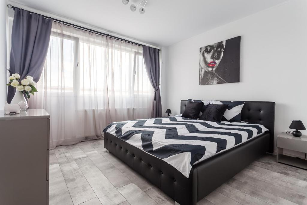 a bedroom with a black and white bed and a window at Bright House in Bucharest