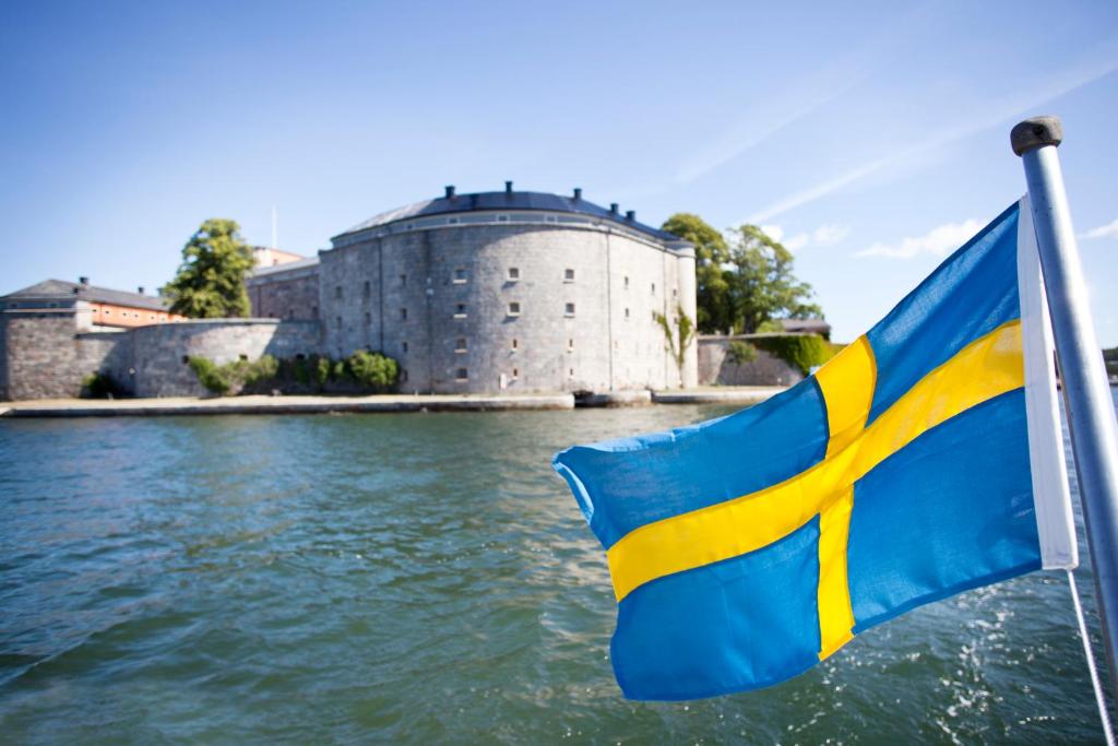 a flag on a boat in front of a castle at Kastellet Bed & Breakfast in Vaxholm