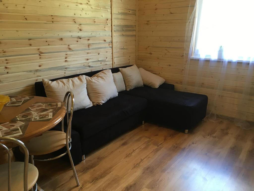 ein schwarzes Sofa mit weißen Kissen in einem Zimmer in der Unterkunft Mazligzdiņa in Višķi