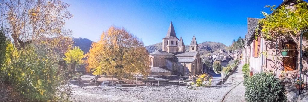 een schilderij van een gebouw met een kerk bij Le Compostelle de Conques in Conques