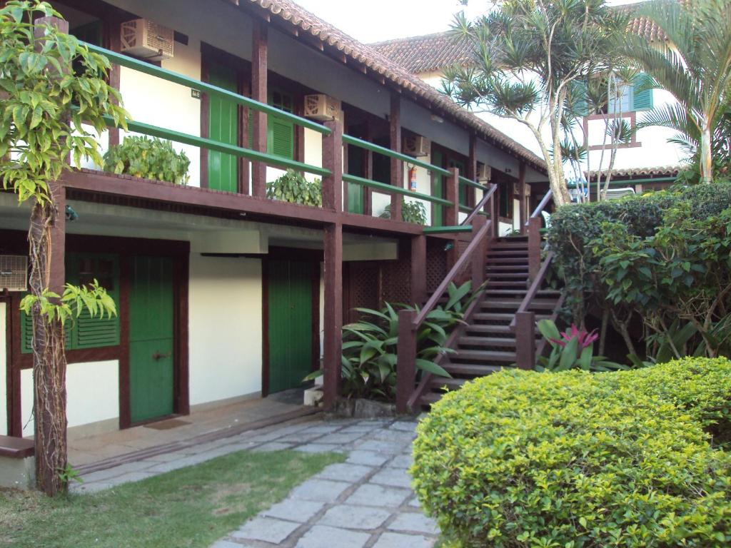 a building with green doors and stairs in a yard at Barla Inn Suites in Búzios