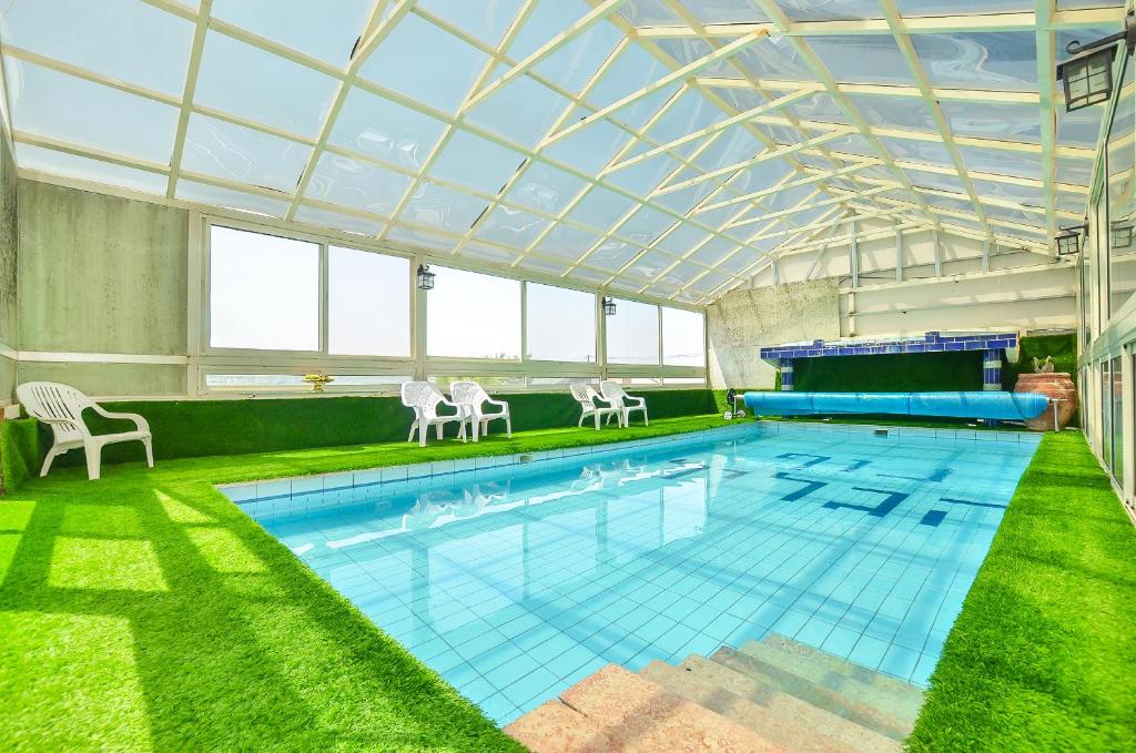 una gran piscina con techo de cristal y sillas blancas en ביקתות נוף הגליל, en Ya‘ara