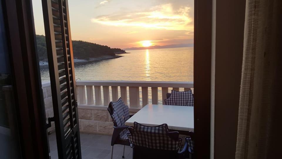 a table and chairs on a balcony with a view of the ocean at Apartments Davor in Postira