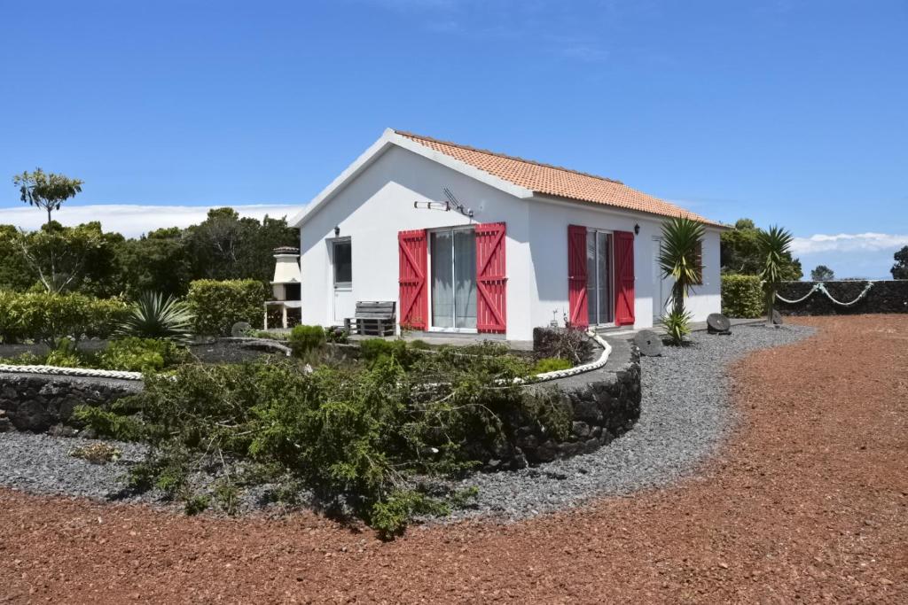 a white house with red doors and a gravel yard at Adega Mourato in Bandeiras