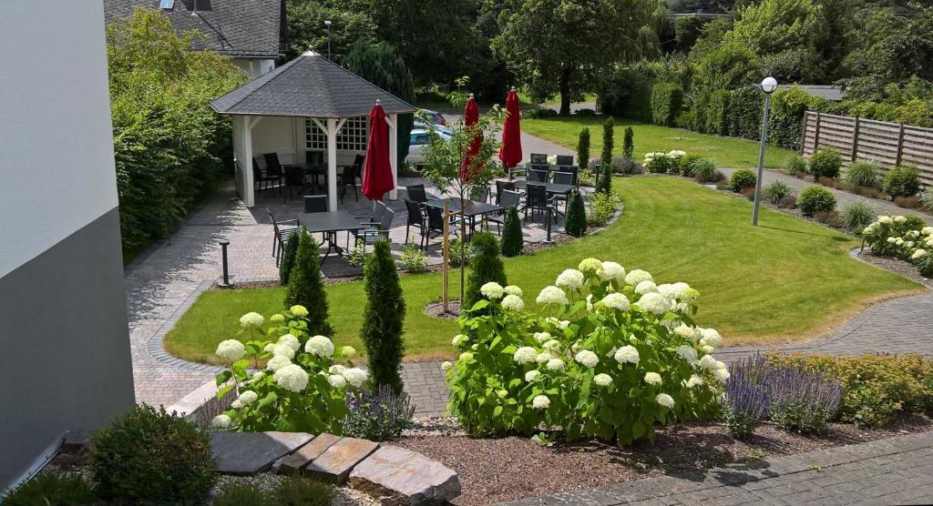 un jardín con flores blancas, mesas y sombrillas en Gästehaus Freimuth en Mesenich