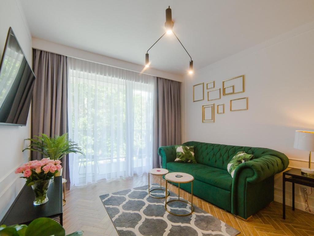 a living room with a green couch and a window at Apartament 59 Dwie Sosny in Ustronie Morskie