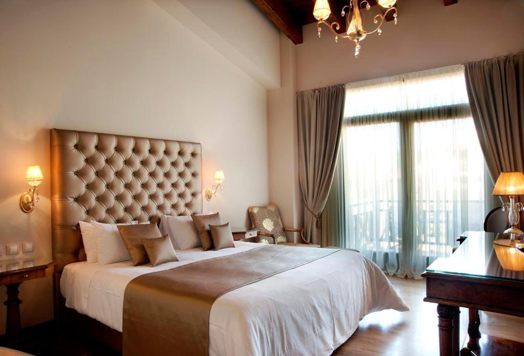1 dormitorio con 1 cama grande y ventana grande en Tagli Resort & Villas en Arachova