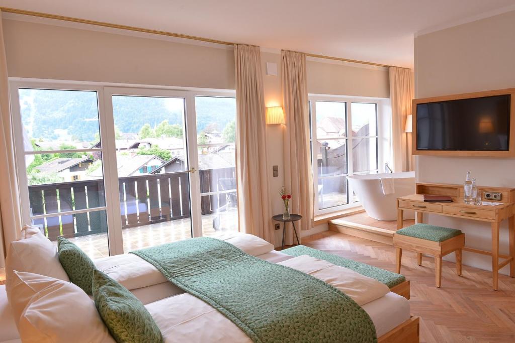 a hotel room with a bed, table, chairs and a tv at Biohotel Garmischer Hof in Garmisch-Partenkirchen