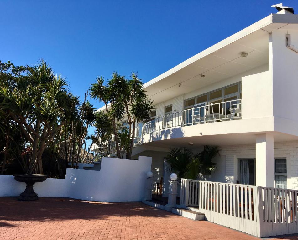 a white house with palm trees in front of it at La Mer Guesthouse in Port Elizabeth