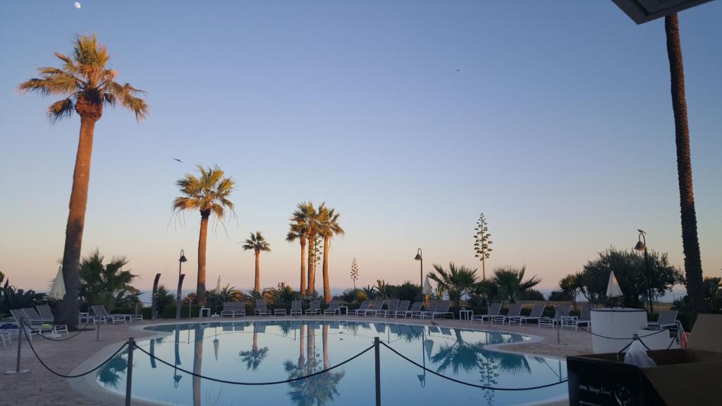una gran piscina con palmeras y sillas en Case Vacanze Bellavista, en Realmonte