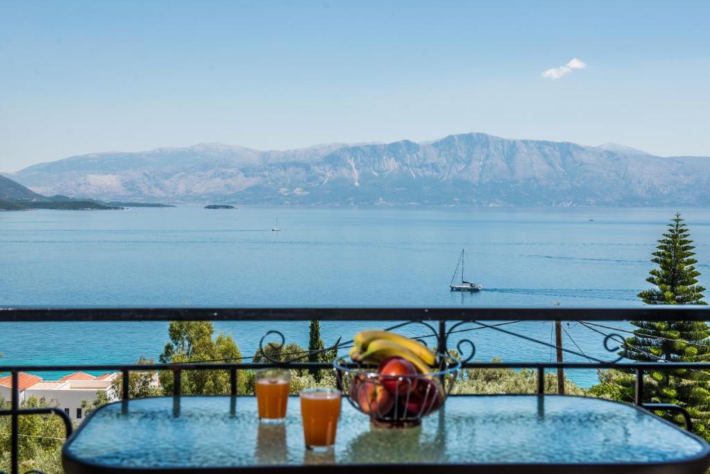 uma mesa com uma tigela de frutas e bebidas numa varanda em Aggeliki Apartments em Nikiana