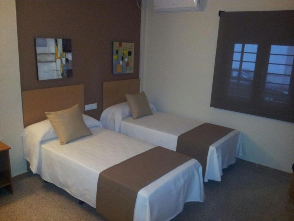 a hotel room with two beds and a window at H. Ciudad de Lepe in Lepe