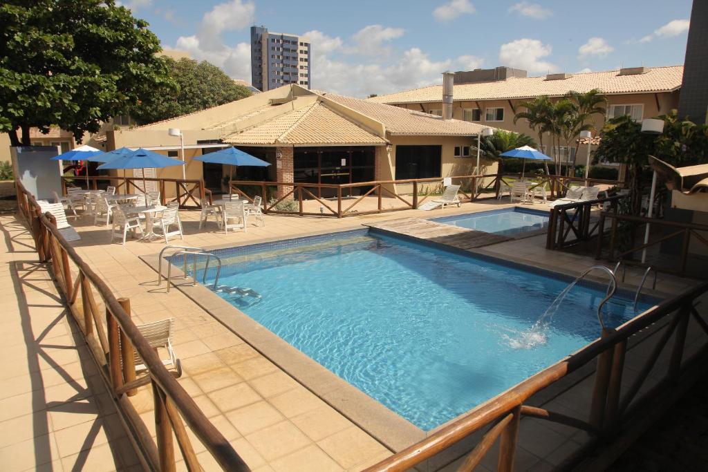Hotel Pousada do Sol في أراكاجو: مسبح فيه كراسي ومظلات على مبنى