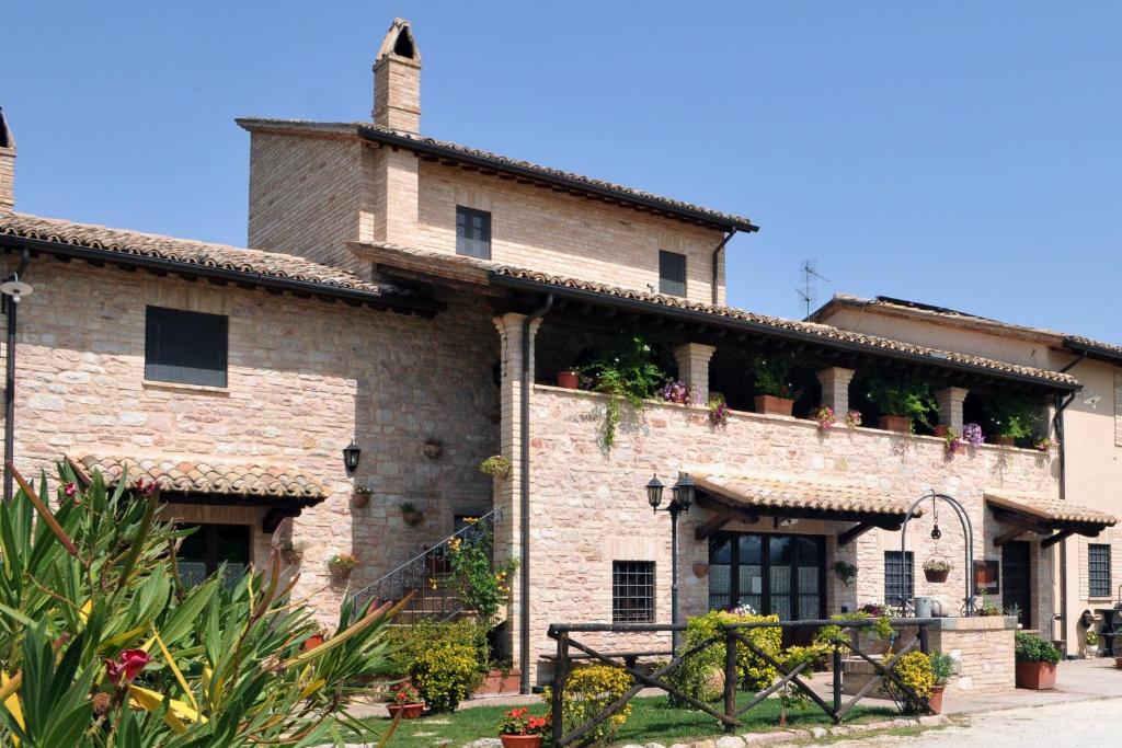 un antiguo edificio de piedra con plantas en el techo en Terre Del Cantico Country House en Spello