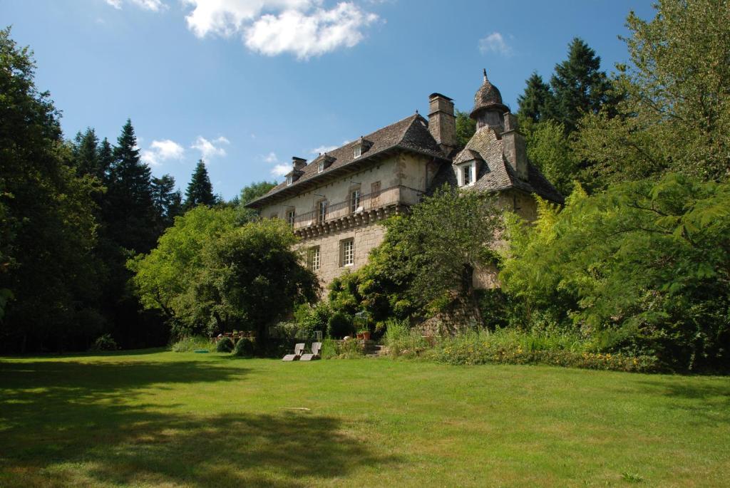 een oud gebouw in een grasveld met bomen bij Gites Chateau le Bois in Saint-Julien-aux-Bois