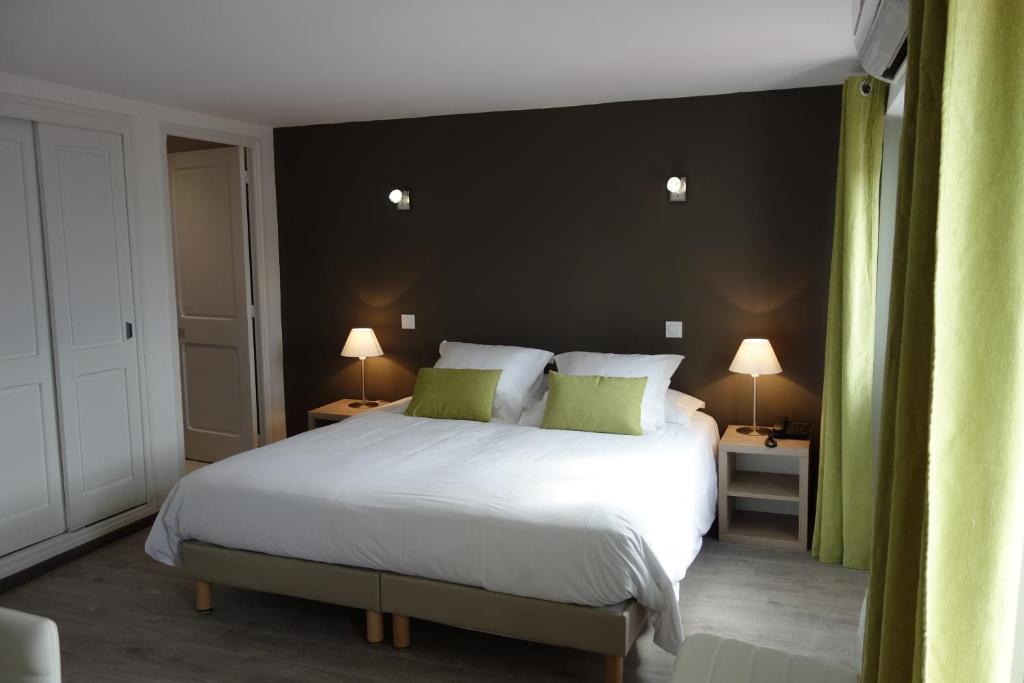 sypialnia z dużym białym łóżkiem z zielonymi poduszkami w obiekcie Hotel le Préjoly w mieście Saint-Vallier-de-Thiey