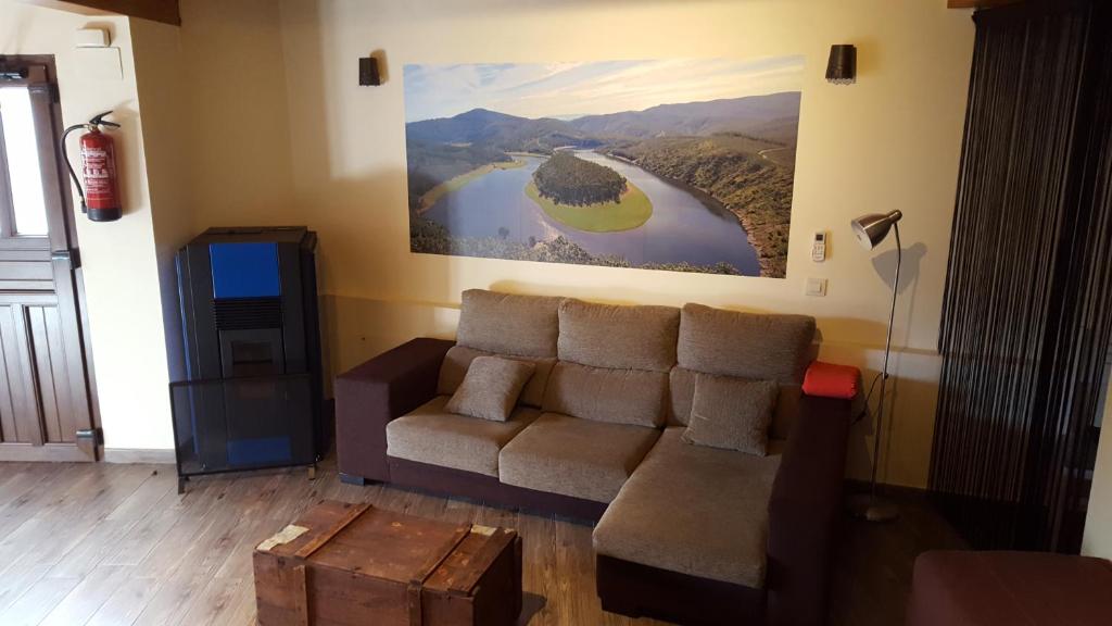 a living room with a couch and a painting on the wall at Casa Rural El Peral in Caminomorisco