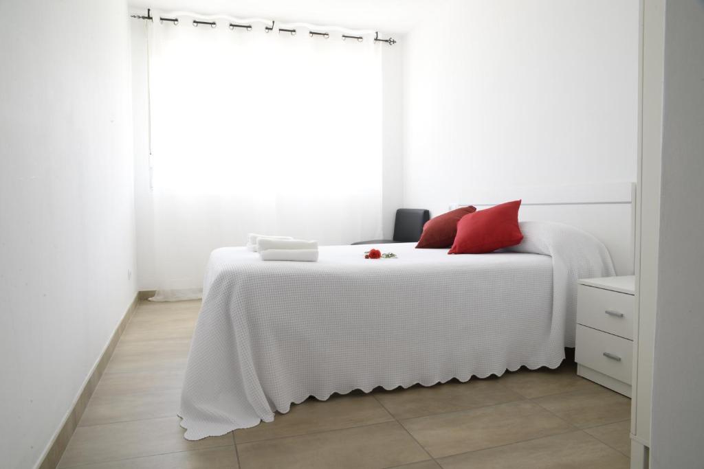 Dormitorio blanco con cama blanca y almohadas rojas en Albergue Mar de Fora en Finisterre