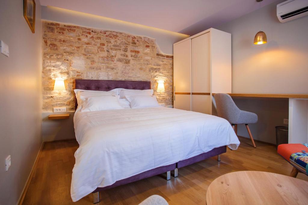 a bedroom with a white bed and a brick wall at Mijama suites in Split