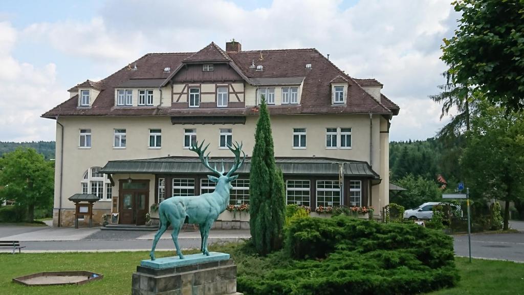 une statue de cerf devant un bâtiment dans l'établissement Parkhotel Forsthaus, à Tharandt