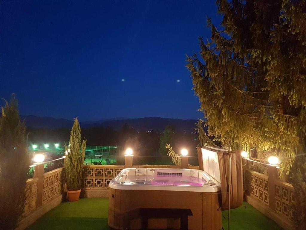 una bañera de hidromasaje en la parte superior de un patio por la noche en Complex Turistic Gura Jgheabului, en Oţelu Roşu