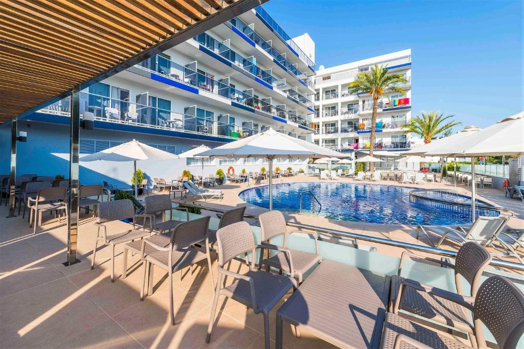 a swimming pool with chairs and umbrellas next to a building at Hotel Vista Park in Can Picafort