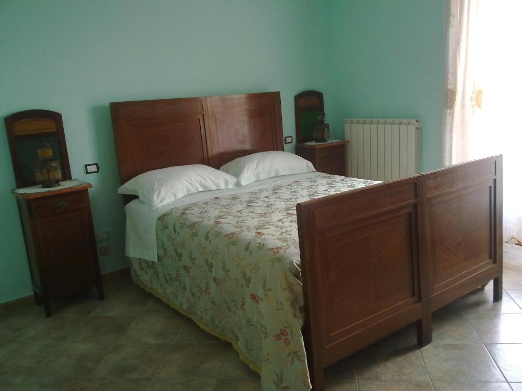 una camera da letto con un grande letto in legno con cuscini bianchi di Agriturismo le Cammarose a Felitto