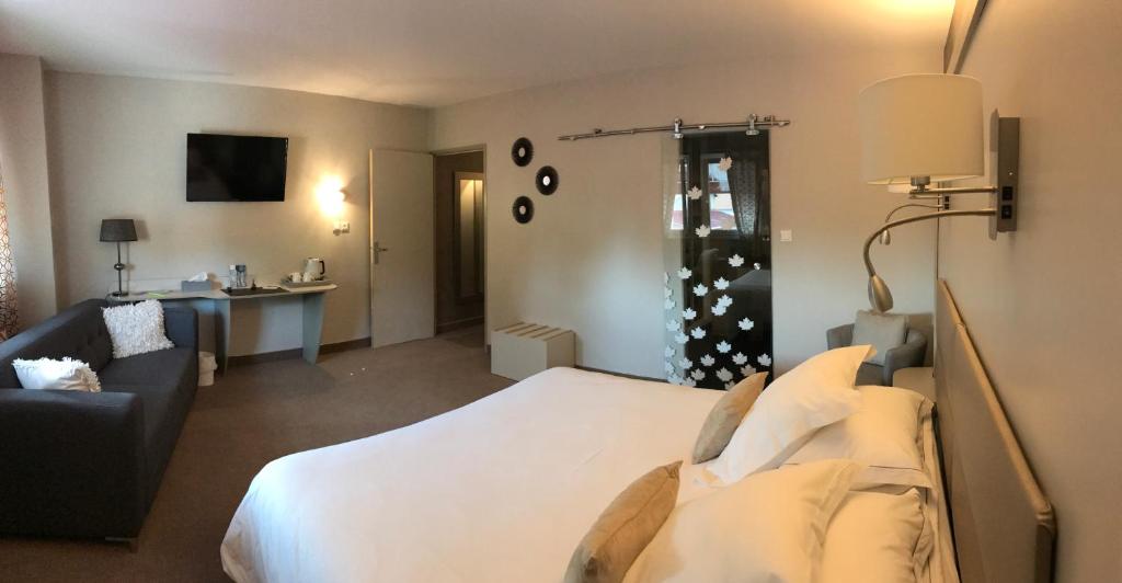 VillersexelにあるHotel Spa Le Relais Des Moinesのベッドとリビングルームが備わるホテルルームです。