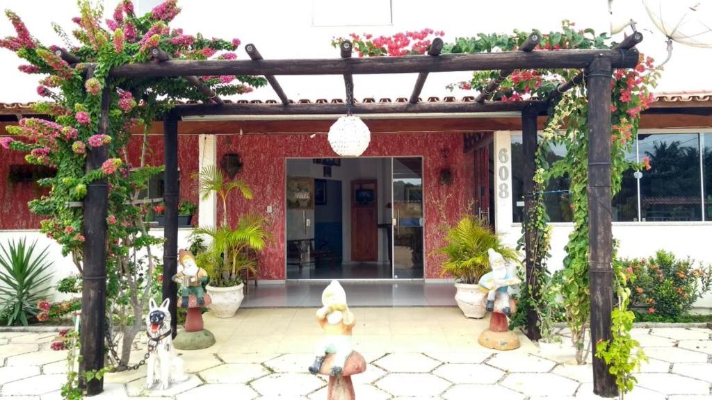 um arco com flores e estatuetas em frente a um edifício em Pousada Miosotis em Nova Viçosa