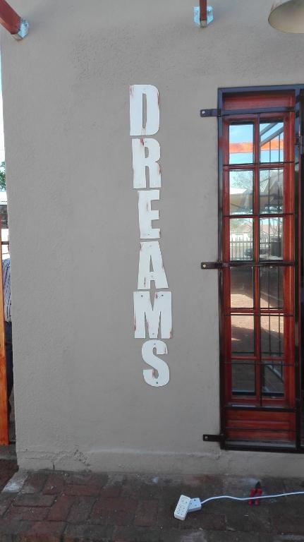 a white building with a door and a sign on it at Dreams in Beaufort West