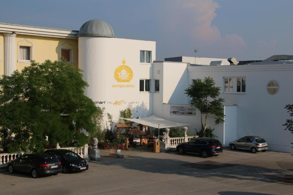 a white building with cars parked in a parking lot at Hotel Freizeittempel in Wiener Neustadt