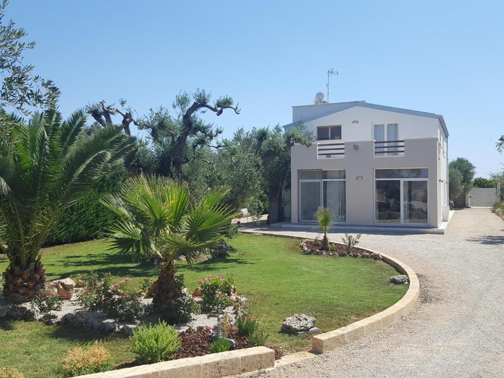 una casa bianca con palme e un vialetto di Villetta Via Lecce a Galatone