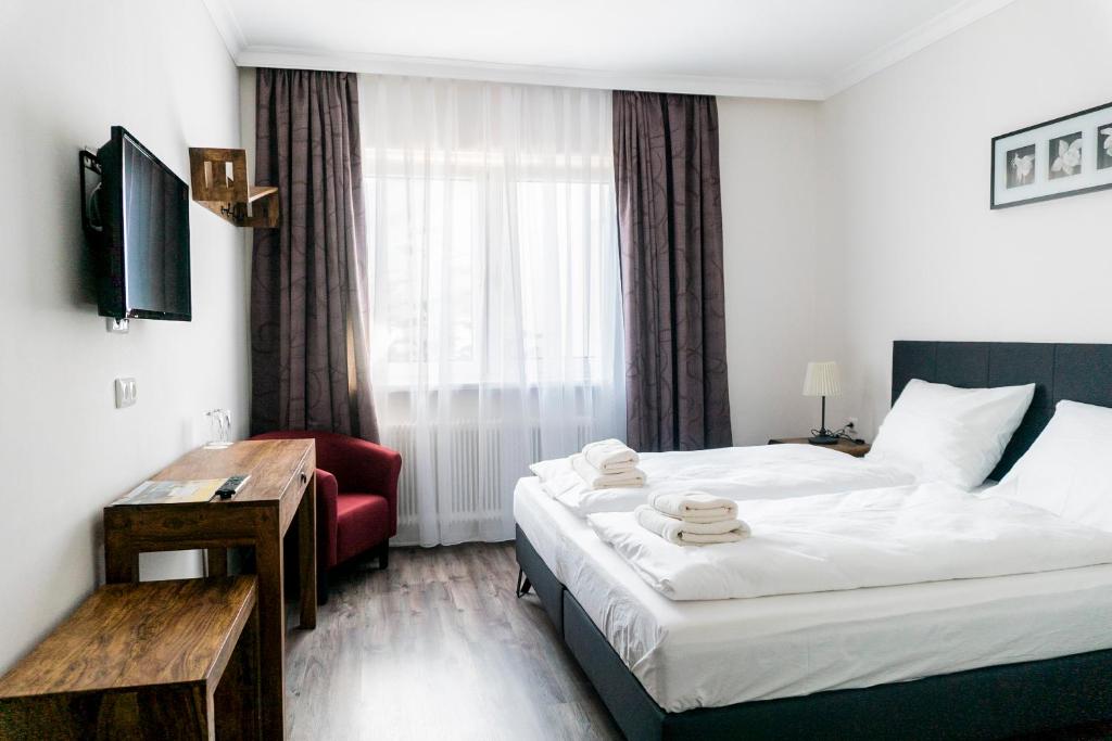 グミュントにあるPension zum Meridiansteinのベッドと赤い椅子が備わるホテルルームです。