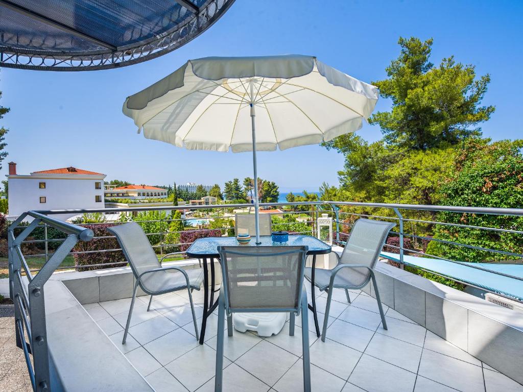 a table with chairs and an umbrella on a balcony at Aegean Residence - F & B Summer Collection in Kallithea Halkidikis