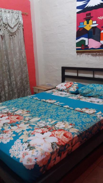Hospedaje Dannita B&B في بويرتو لوبيز: غرفة نوم بسريرين ولوحة على الحائط