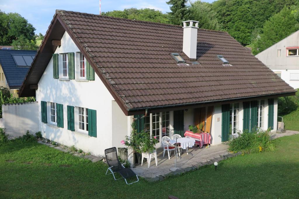 uma casa branca com persianas verdes, uma mesa e cadeiras em B&B Sigrid Braun-Budde em Bettingen