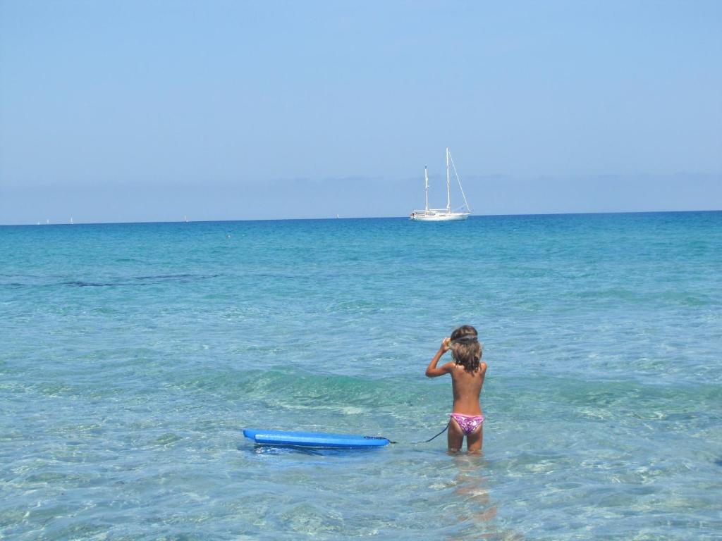 シニスコーラにあるVillaggio Camping Calapinetaの筏を持って海に立つ少女
