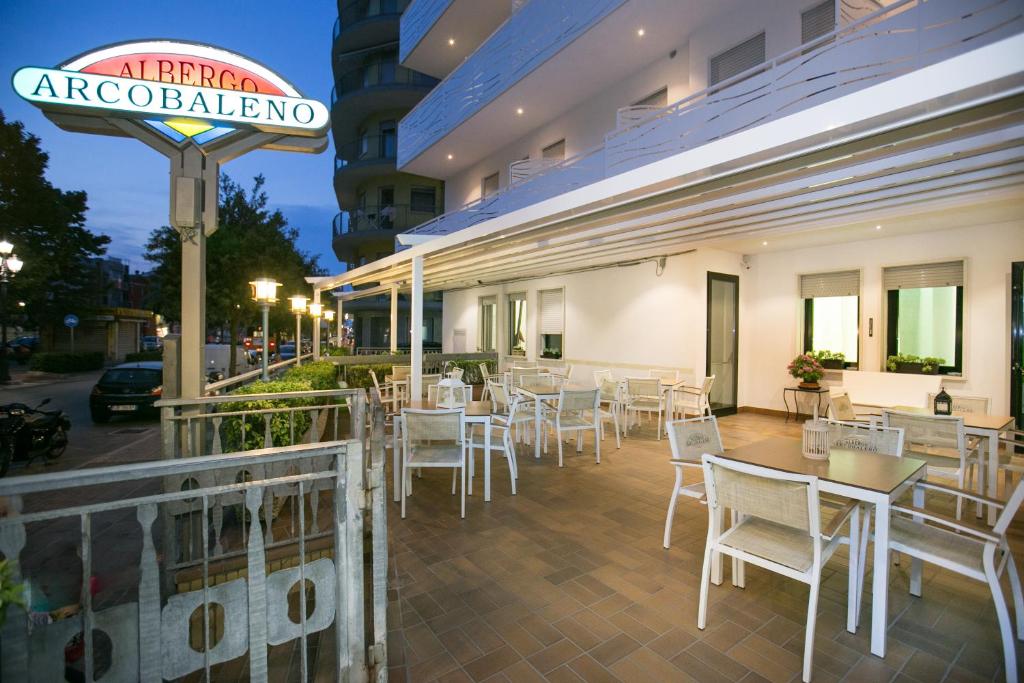 un restaurant avec des tables et des chaises blanches et un panneau dans l'établissement Albergo Arcobaleno, à Sottomarina