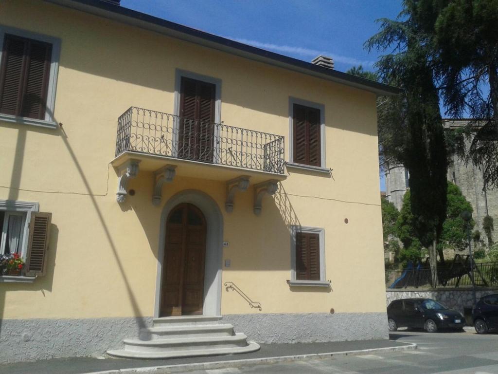 a yellow house with a balcony on top of it at Casa Lara in Massa Marittima