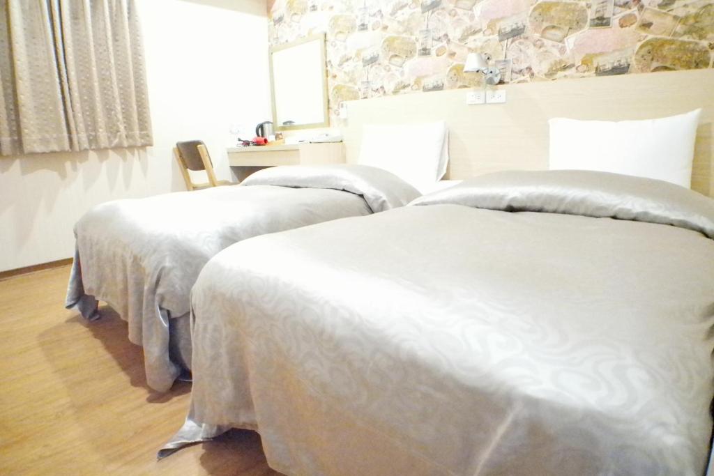 a bedroom with two beds with white sheets at Sanduo Hotel in Kaohsiung