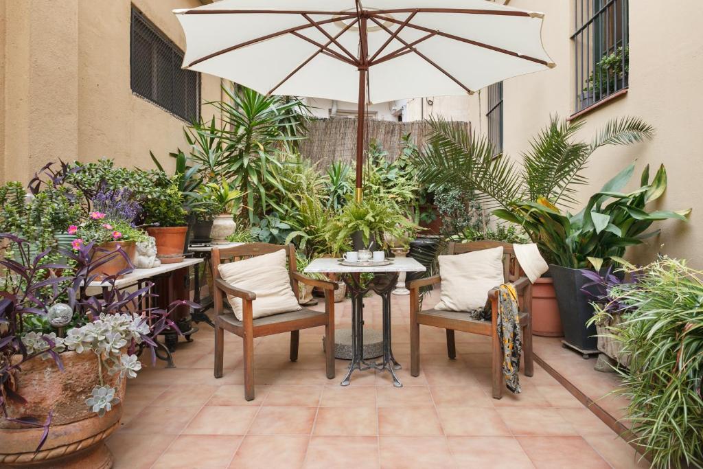 巴塞隆納的住宿－天井巴塞羅那公寓，庭院配有桌椅和遮阳伞。
