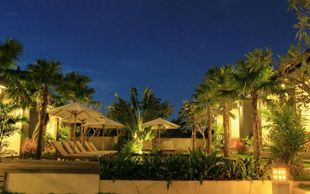 a resort with chairs and umbrellas and palm trees at night at D'padang in Uluwatu