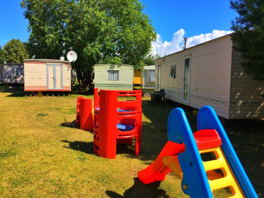 a group of playground equipment in a yard next to a trailer at Karavanai "Aušroje" in Šventoji